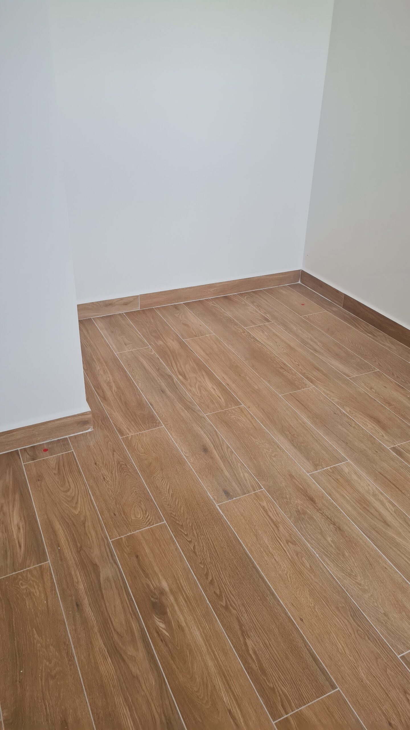 Piso com revestimento cerâmico amadeirado em vistoria de imóvel novo.